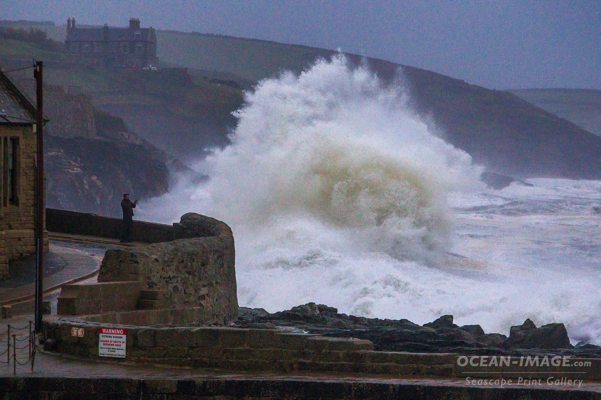 A man takes a picture of a massive breaking wave