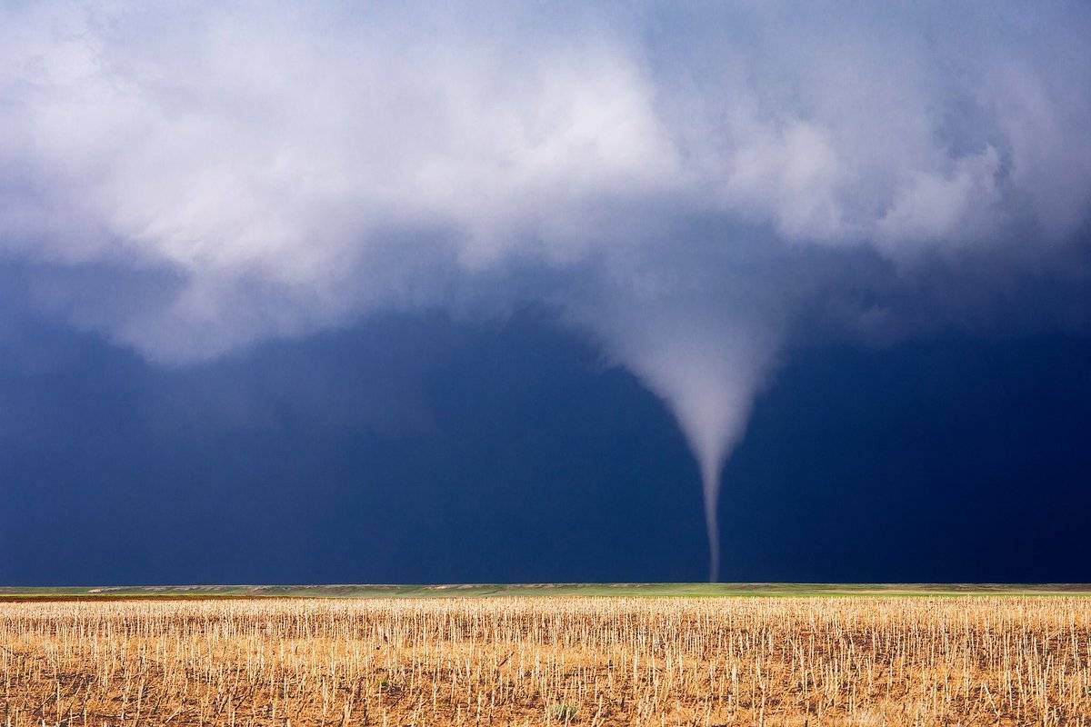 A sunlit tornado begins its journey across the vast farm fields of western Nebraska by John Sirlin @SirlinJohn
