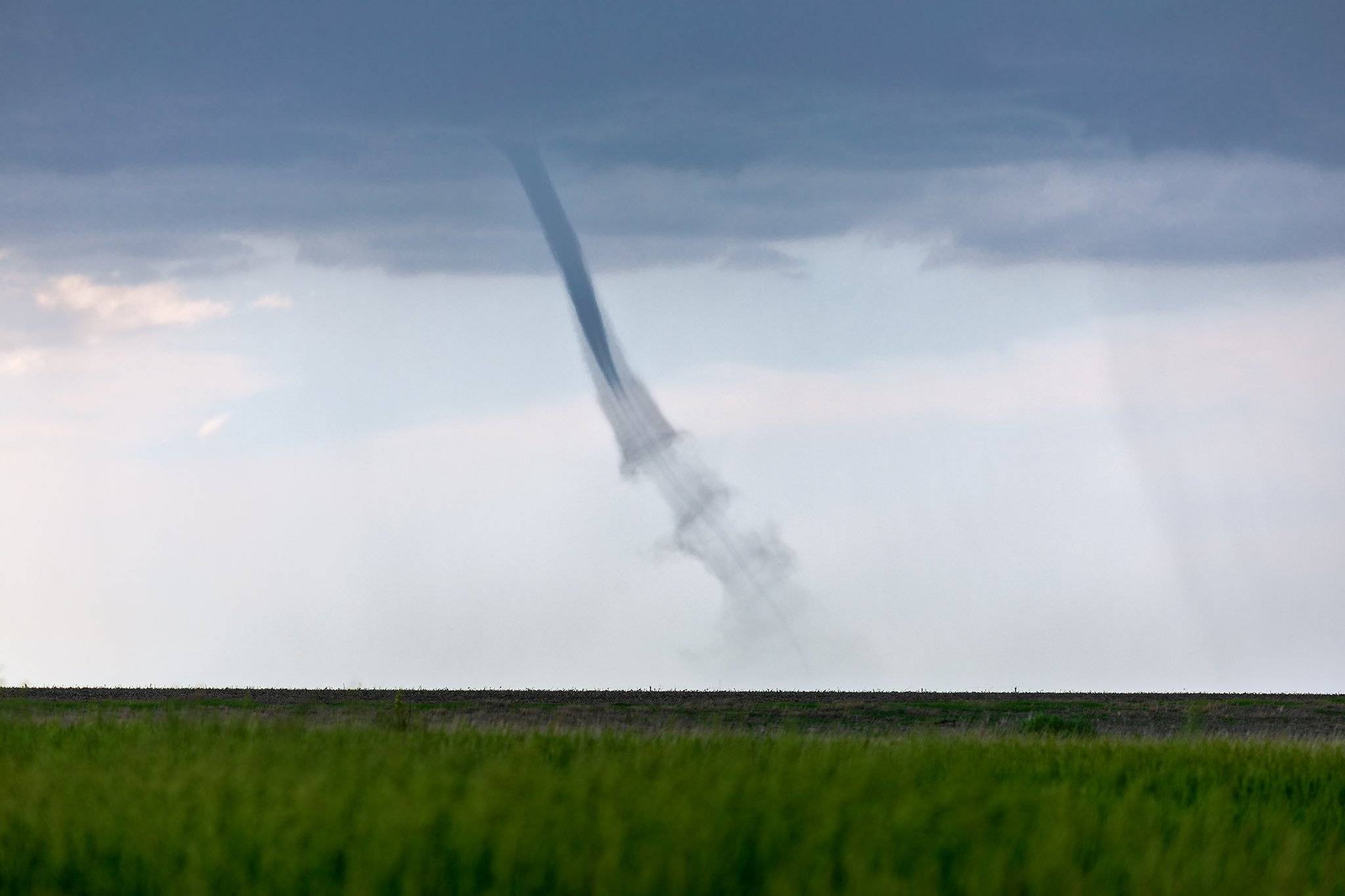 A landspout tornado with beautiful, helical vortex sheathing, dancing across a farm field near St. Francis, Kansas by John Sirlin @SirlinJohn