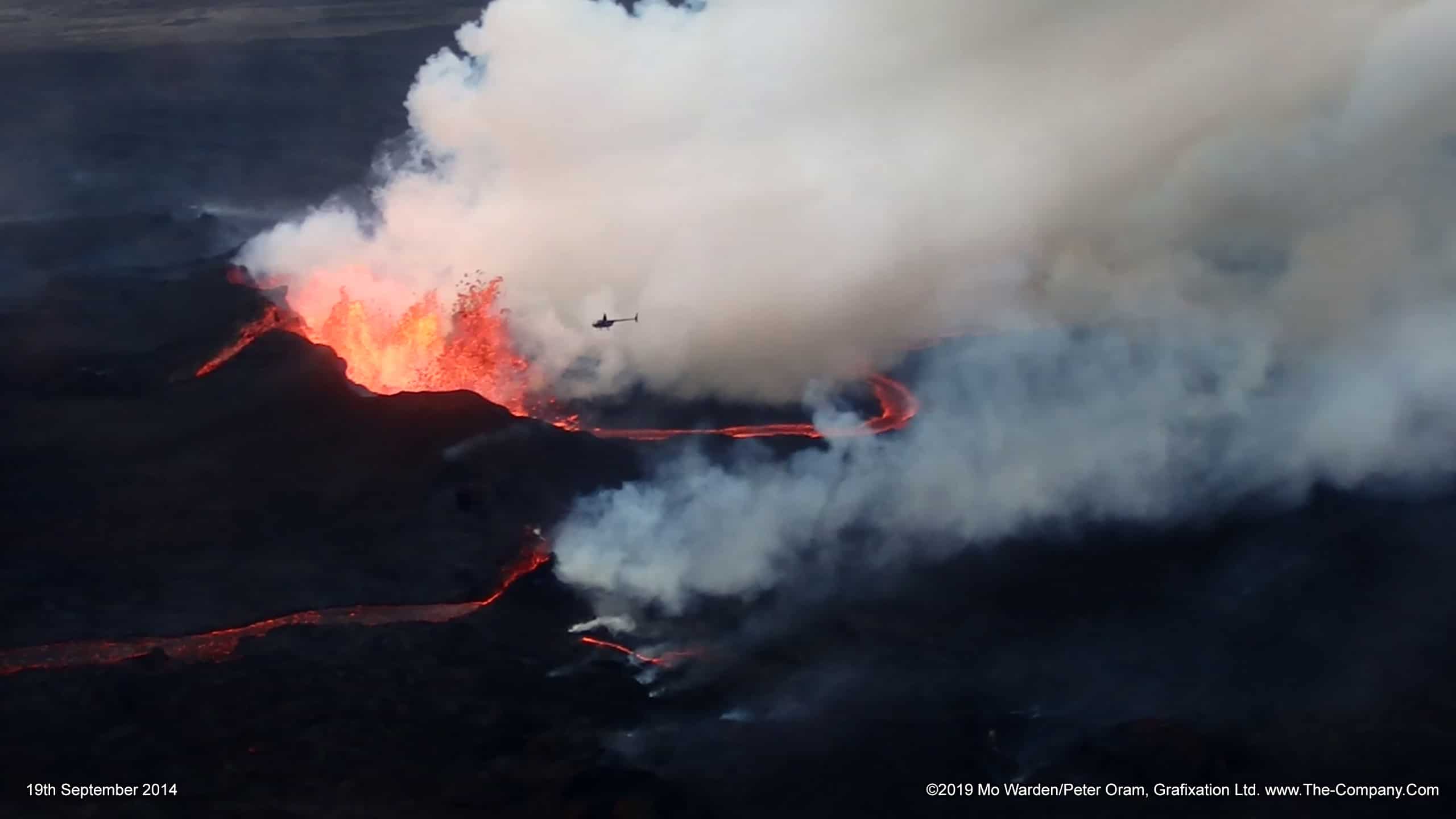 A helicopter lends scale to the lava fountains.