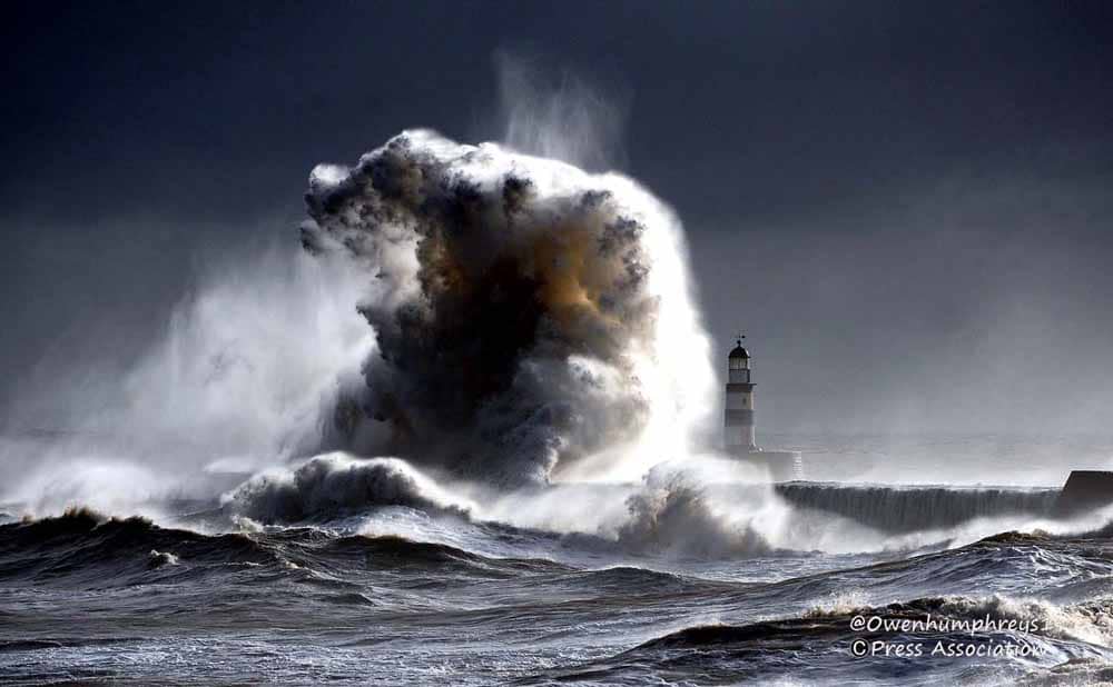 giant wave crashing over a lighthouse at Seaham in Durham UK